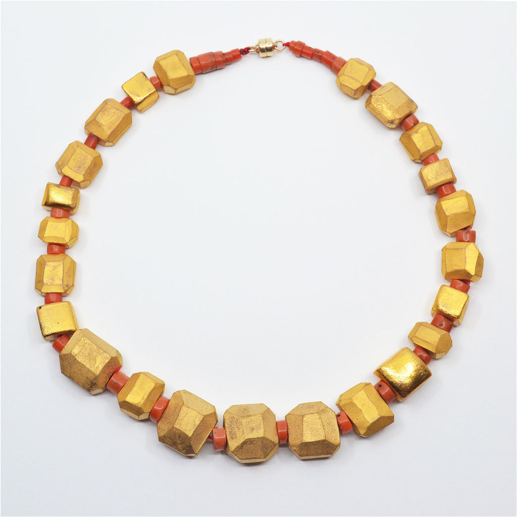 Unique golden porcelain beads made by hand, glazed with matte 22 karat gold with patina finish, and vintage orange-red coral beads. with magnetic clasp.