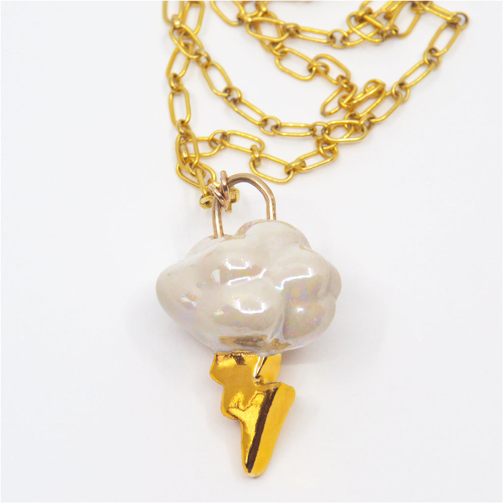 This unique pendant necklace is made by hand. The pendant is handcrafted of porcelain, the cloud shape is glazed with mother of pearl luster, and the lightning bolt is glazed with 22 karat gold. The pendant is attached to a gorgeous 14 karat gold-filled chain.