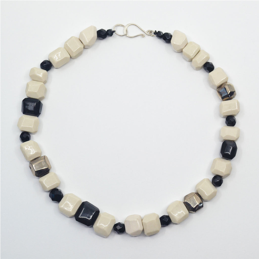 Unique porcelain choker necklace, made of hand-faceted porcelain beads. The beads are glazed in creamy white, and a few beads in glossy black. With faceted vintage black glass beads. The clasp is sterling silver hook. 