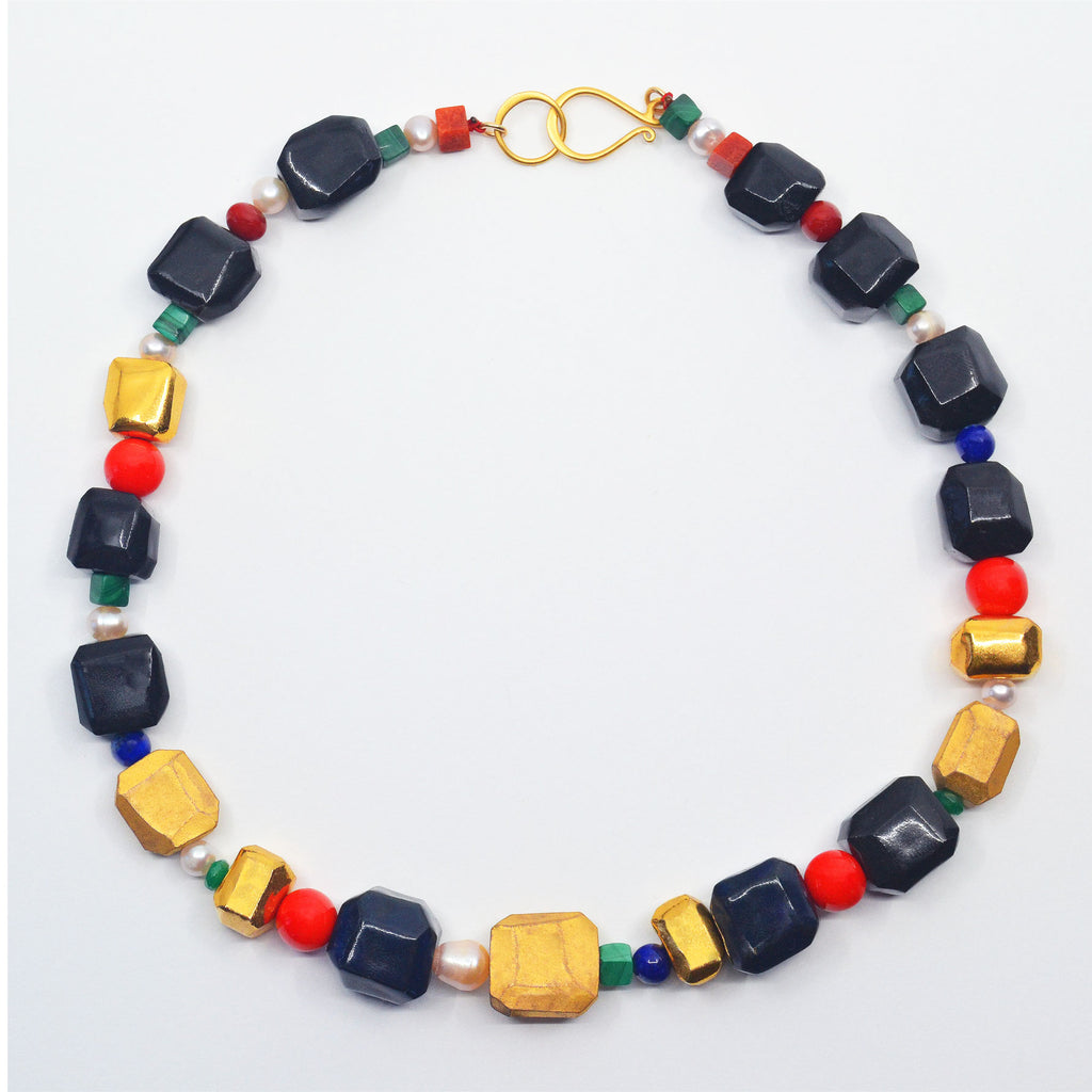 Unique Porcelain bead necklace. The beads are handcrafted and faceted, they are glazed dark blue, and black, as well as shinny and matte 22 karat gold luster glaze. With vintage pearls and glas beads, and semi-precious stones, such as lapis lazuli, malachite, coral and emerald. Golden hook clasp.  