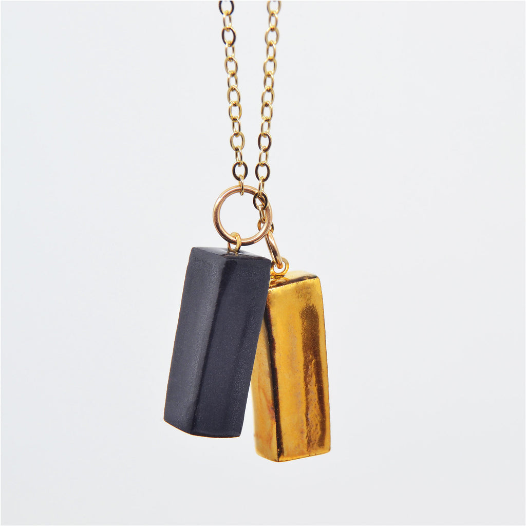 This unique porcelain pendant necklace is made of two handcrafted porcelain beads. The beads are glazed in black and gold. They are attached to 14 karat gold-filled rings and long chain. The pendants can slide up and down and can be worn to your liking.