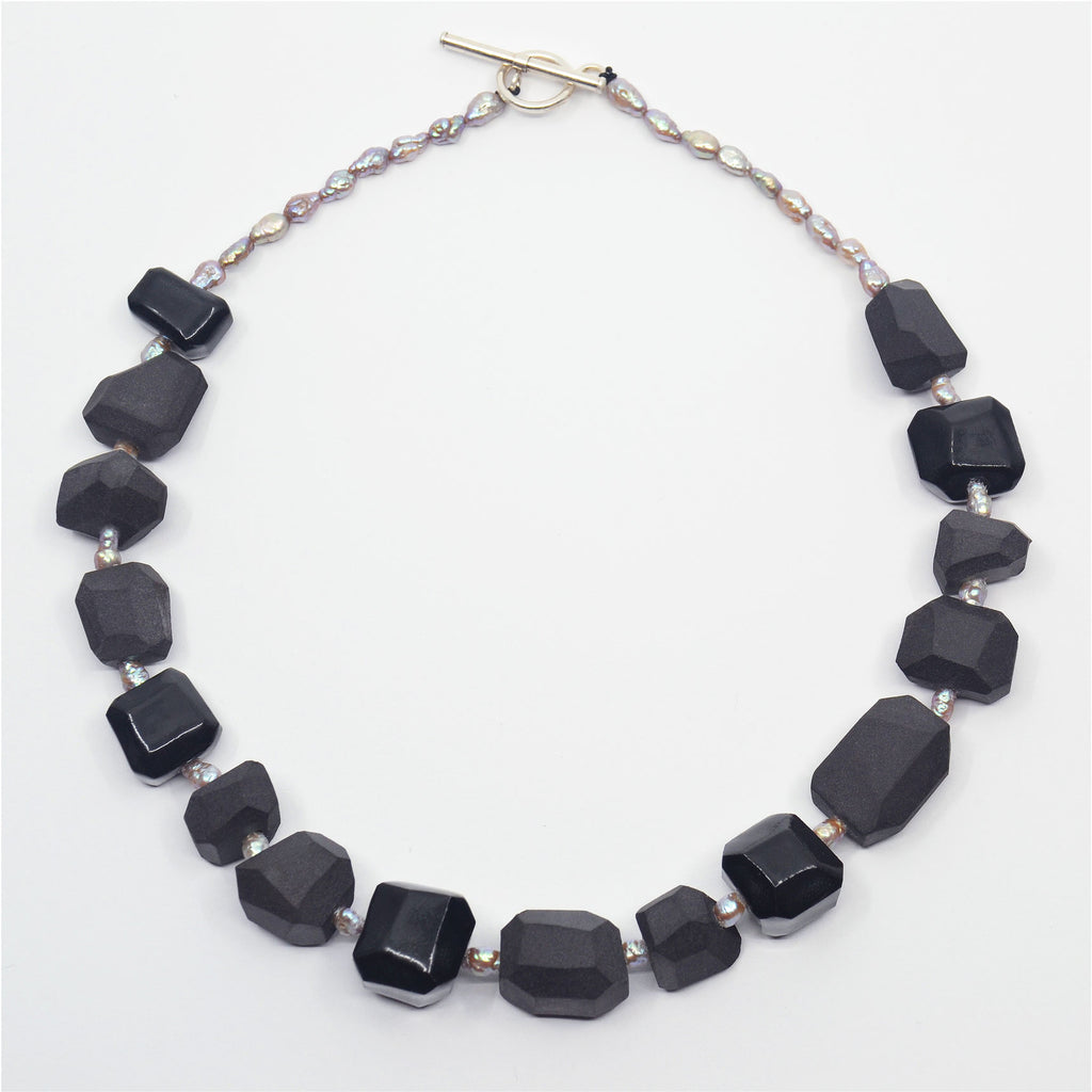 Unique Choker necklace with black porcelain beads, hand made and faceted. The beads are unglazed with a few glazed in glossy black. With salt water pearls in purplish silver color. Sterling silver toggle clasp.