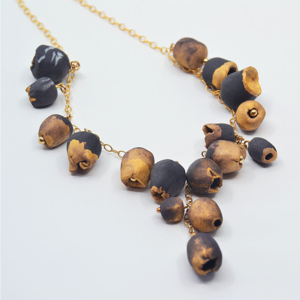 Unique necklace with handmade black and gold dusted porcelain flower buds, on a 14 karat gold filled long chain.
