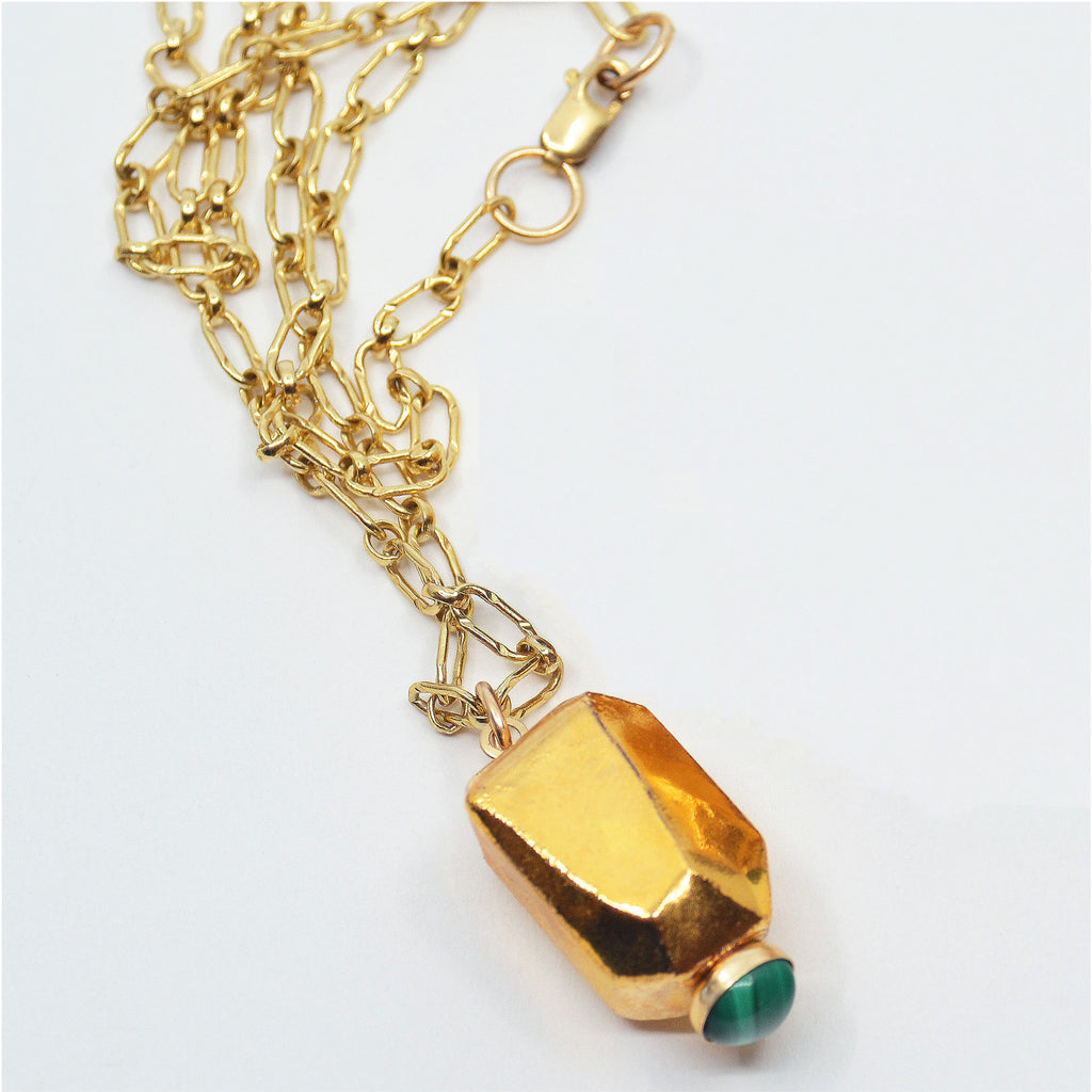 This pretty pendant necklace is handcrafted. The porcelain bead is faceted by hand and glazed with 22 karat gold luster. At the very tip of the gold pendant is a round malachite cabochon in a 14 karat gold-filled bezel setting. The pendant is attached to a 14 karat gold-filled ring and gorgeous chain with clasp.