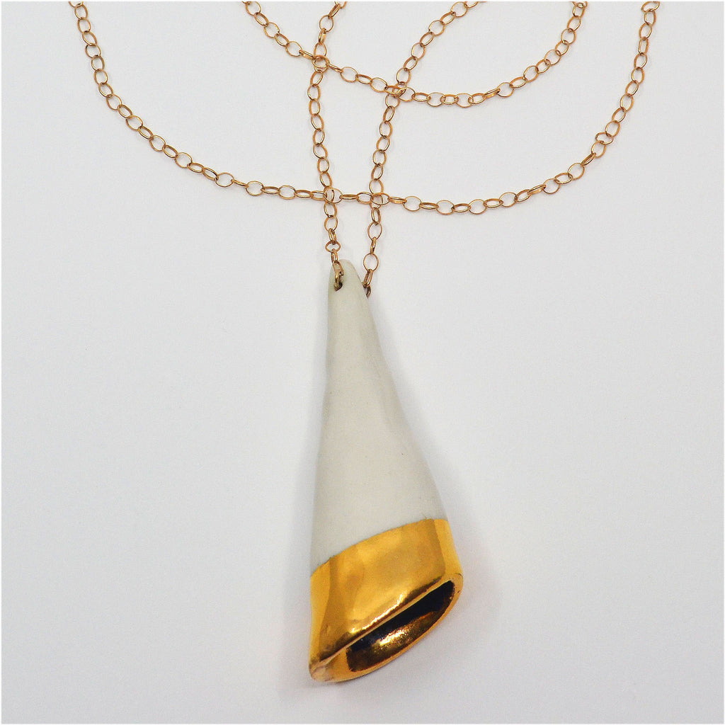 This unique and handcrafted porcelain pendant shaped as a cone. The pendant is white with a 22 karat gold rim at the bottom around the opening of the cone. The pendant is attached to a 14 karat gold-filled chain.