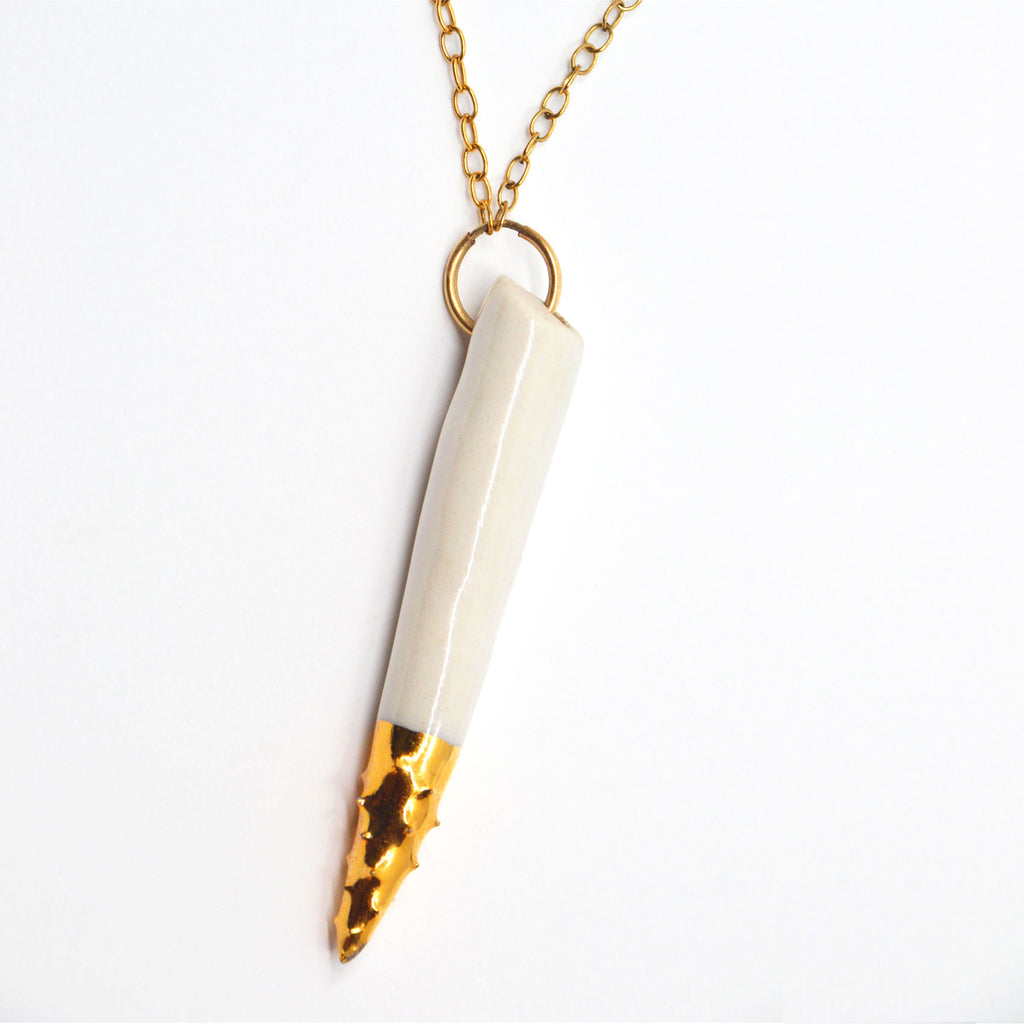 This unique pendant necklace is handmade. The pendant is hand-crafted of white porcelain, the pointy spiked tip is glazed with 22 karat gold. The pendant is attached to a 14 karat gold-filled ring and chain. 