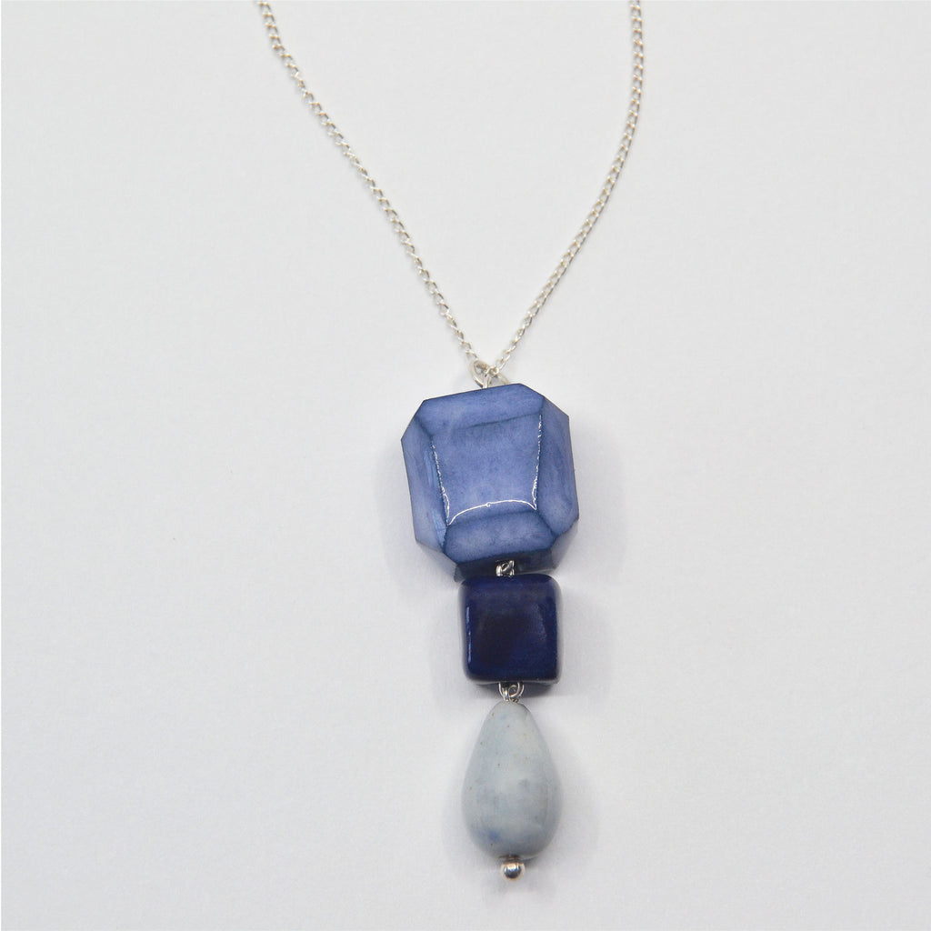 This cute necklace is made by hand, the beads are handcrafted of porcelain and faceted by hand, they are glazed in shades of blue, with a drop shaped dangle bead. The pendant is attached to a fine sterling silver chain with clasp.