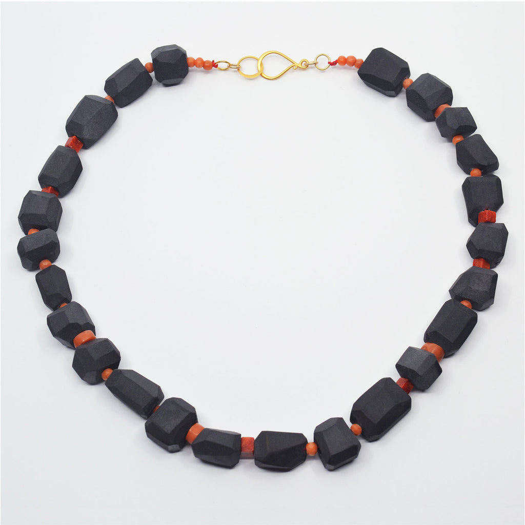 Unique choker necklace with handcrafted black porcelain beads. Each bead is faceted by hand and left unglazed, with vintage coral beads and a golden hook clasp.