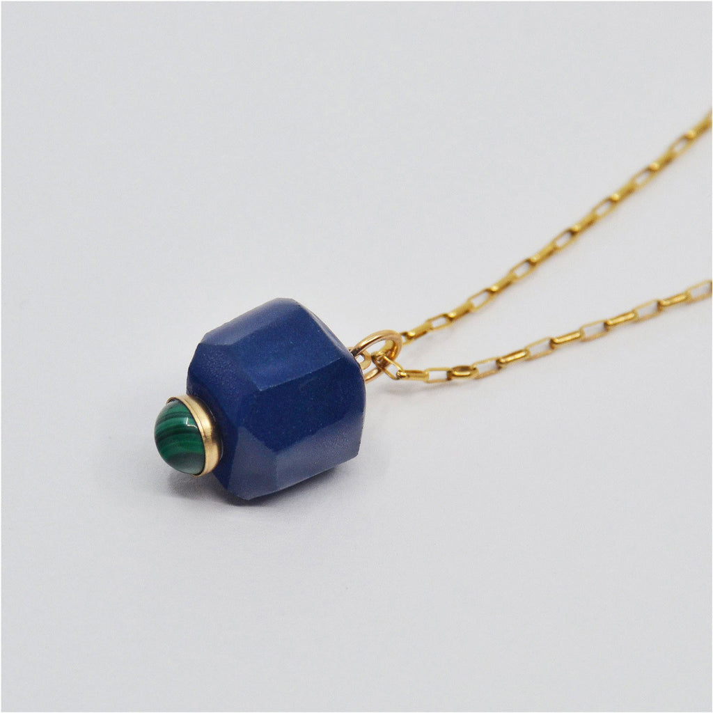 This pretty pendant necklace is handmade. The pendant is crafted of blue porcelain and glazed with a glossy clear glaze. The tip is adorned with a round malachite cabochon in a 14 karat gold-filled bezel setting. The pendant is attached to a 14 karat gold-filled ring and chain with clasp.
