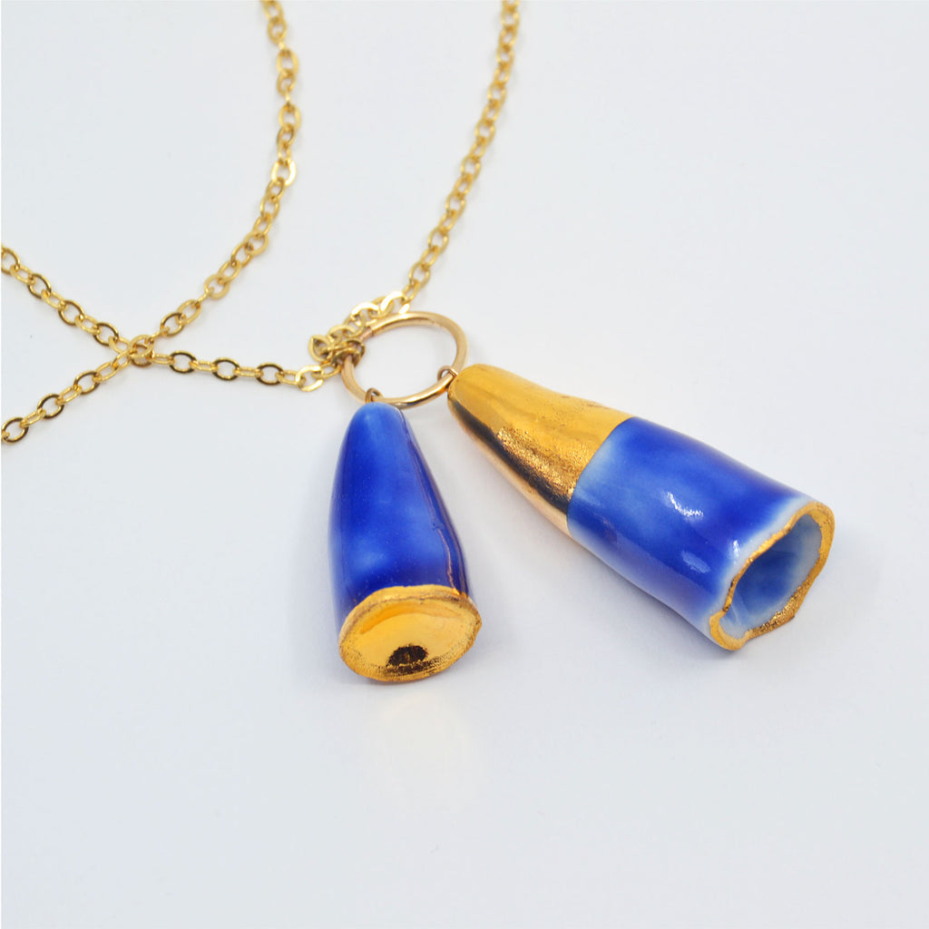 This unique porcelain pendant necklace is handmade. The porcelain beads are in the shape of bluebell flowers. They are glazed in blue and 22 karat gold glaze, and attached to a long 14 karat gold-filled ring and chain. 