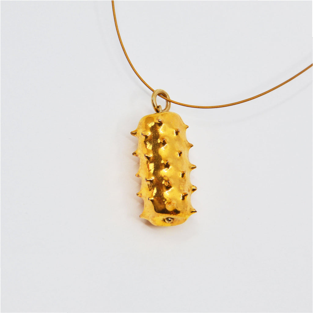 This unique necklace is made by hand. The porcelain bead is hand-crafted in the shape of a cylinder with pointy spikes. It is glazed with shiny 22 karat gold and is attached to a 14 karat gold-filled ring and golden jewelry cord with a 14 karat gold-filled clasp.