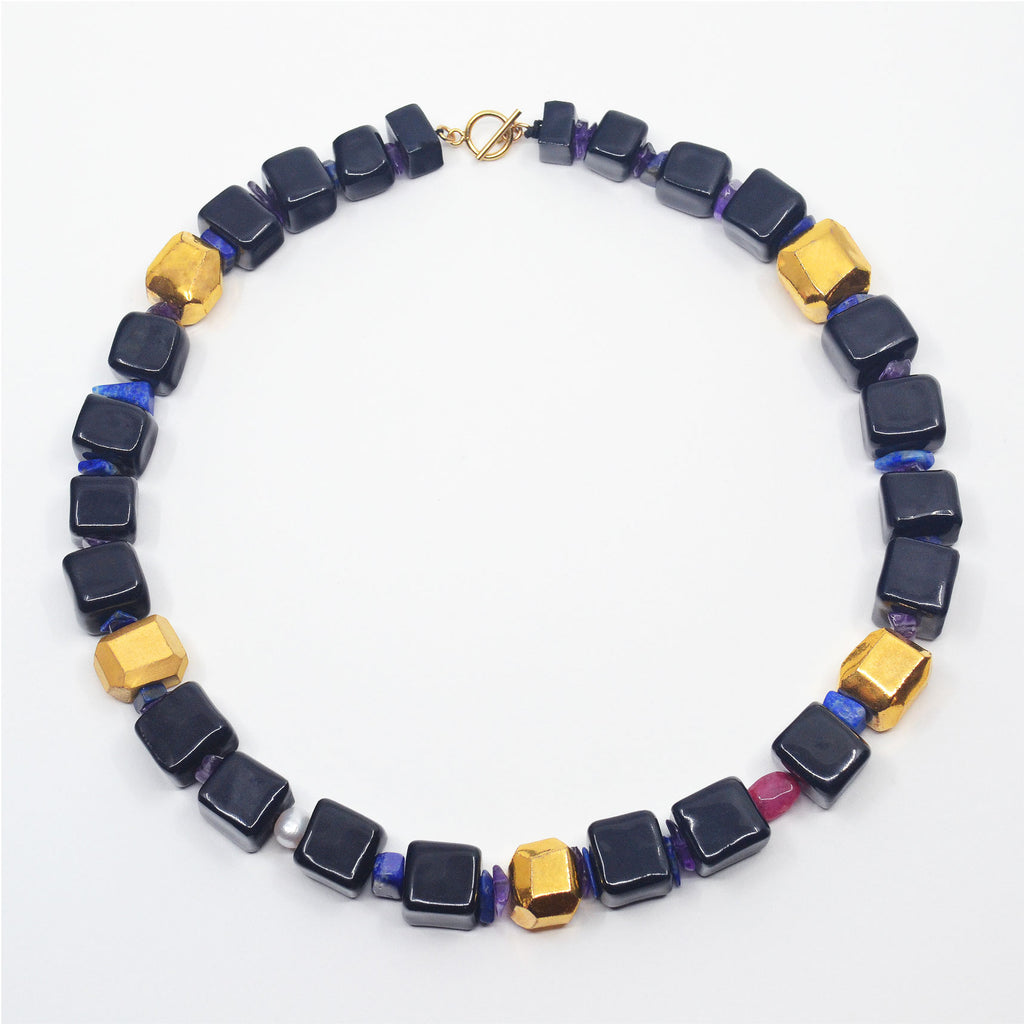 Unique porcelain and gem choker necklace. Handcrafted dark blue glazed porcelain beads, and hand-faceted beads glazed with glossy and matte 22 karat gold luster. With vintage gems and semi-precious stones in pink, blue and purple colors, and pearl. The clasp is a 14 karat gold-filled toggle clasp. 