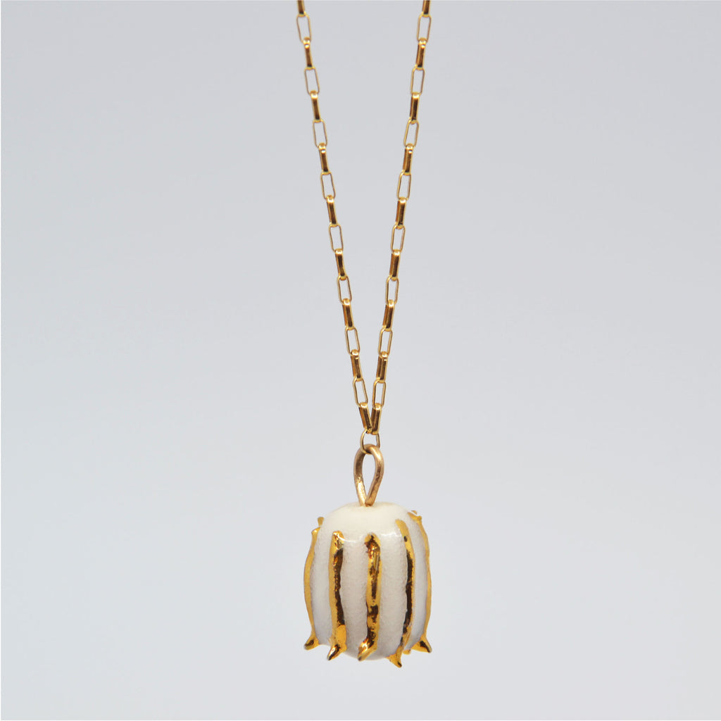 This unique pendant necklace is handmade and consists of a little porcelain flower bud, glazed in white and 22 karat gold glaze. It is attached to a 14 karat gold-filled chain and clasp. 