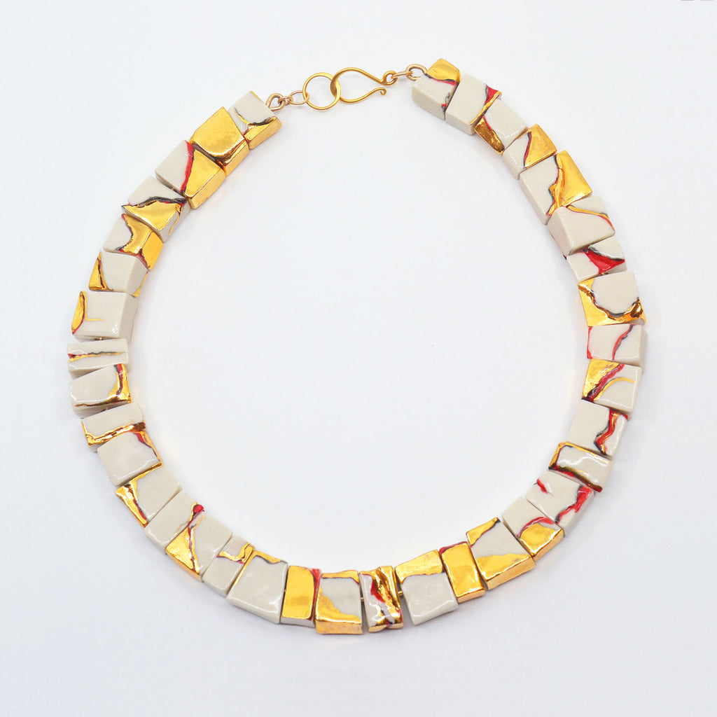 Unique porcelain choker necklace, made with hand-carved white porcelain beads, glazed with 22 karat luster and accents of red glaze. With a golden hook clasp.