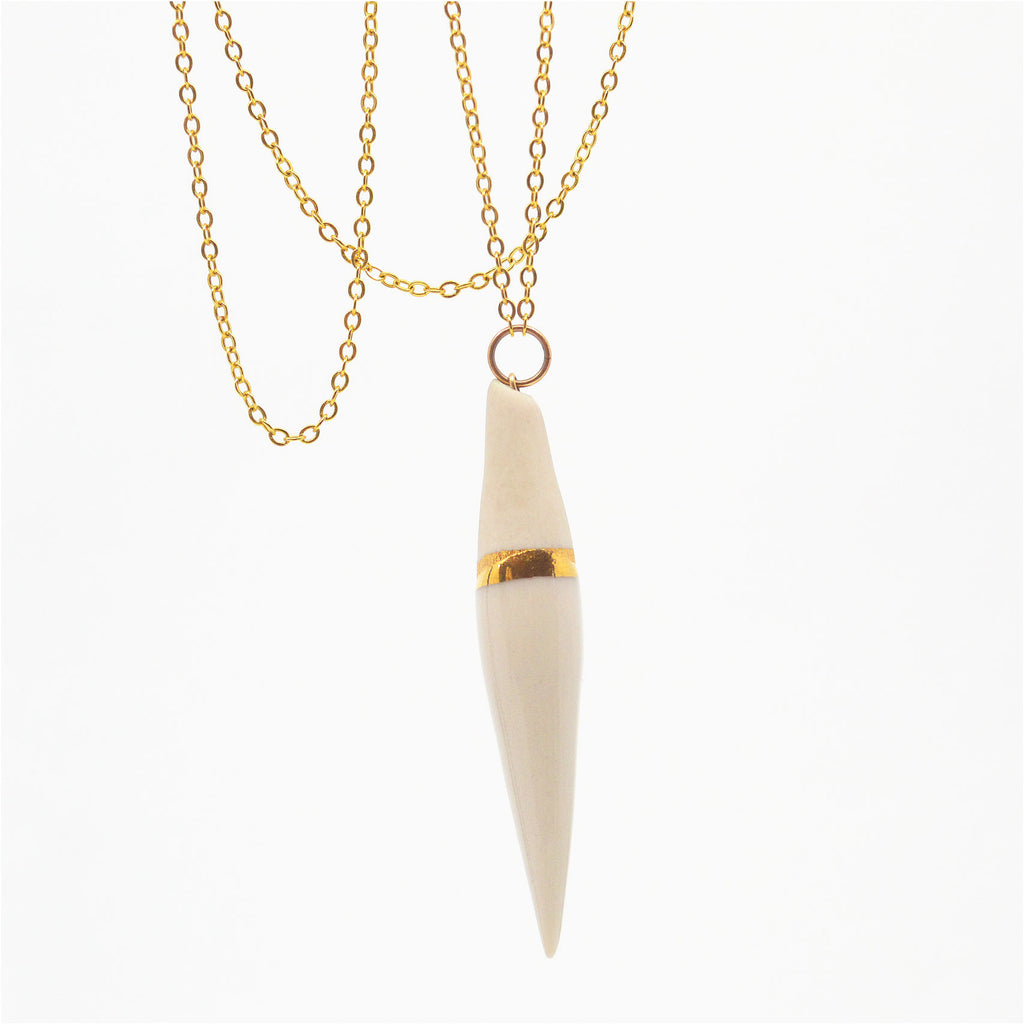 This unique pendant necklace is made of a handcrafted porcelain pendant, which is glazed in white with a 22 karat gold glazed accent, the top of the pendant is left unglazed. The pendant is attached to a 14 karat gold-filled ring and chain. The clasp is a 14 karat gold-filled magnetic clasp.