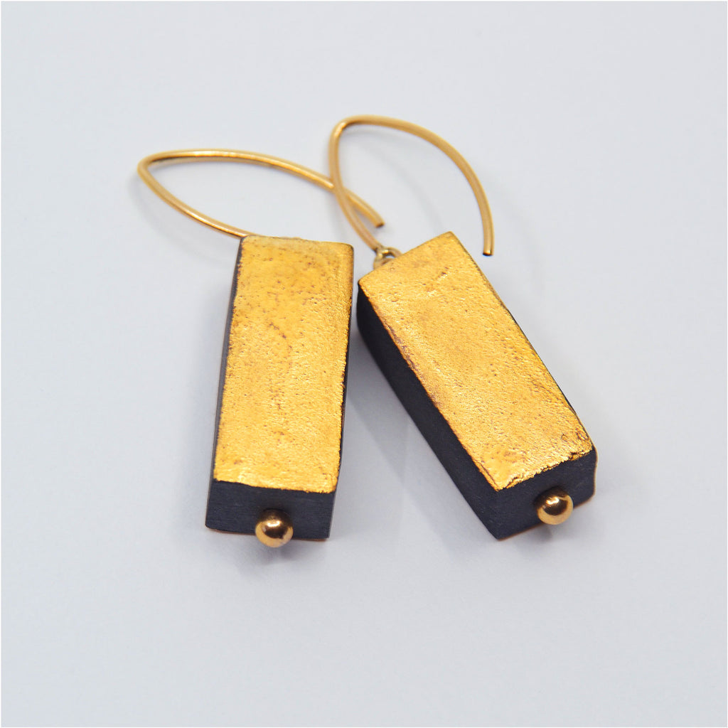 One-of-a-kind porcelain earrings, black porcelain with 22 karat gold glaze on two sides, other sides left unglazed.