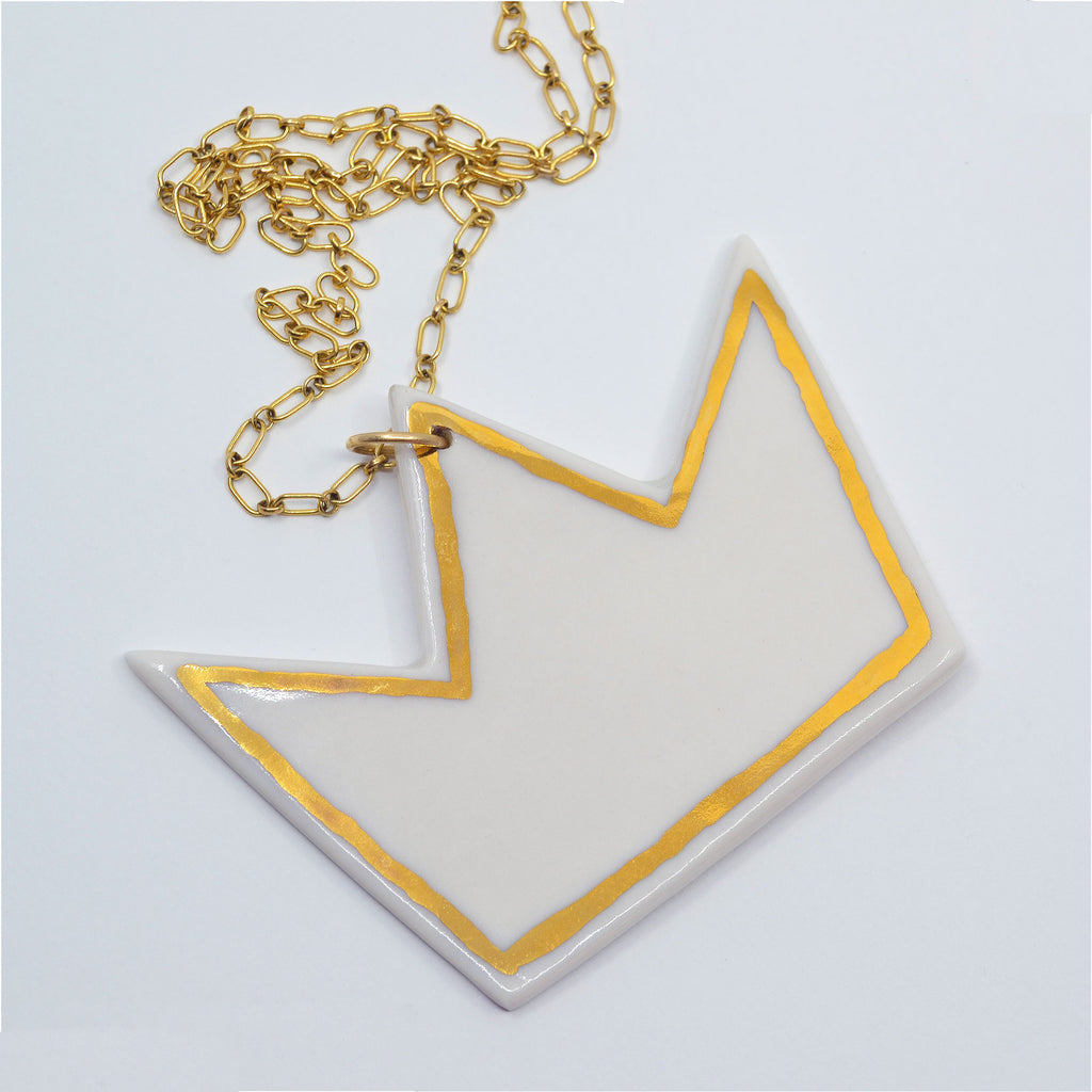 This unique pendant is handcrafted of white porcelain, with accents of 22 karat gold glaze. The pendant is attached to a 14 karat gold-filled ring and gorgeous chain. 