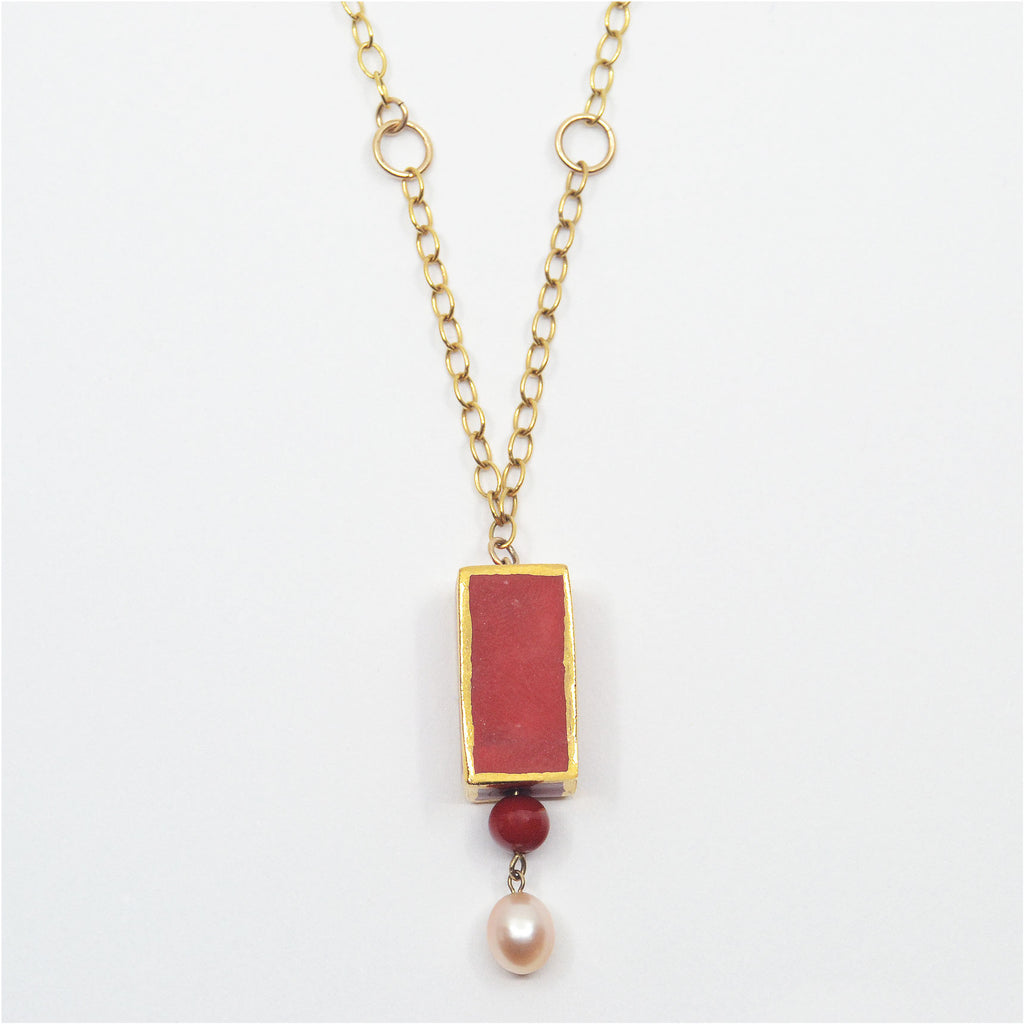 This beautiful unique dangle pendant necklace is handmade. The porcelain bead is handcrafted and glazed in deep red color and 22 karat gold luster. The dangle is made of a vintage red glass bead as well as a oval shaped pearl.